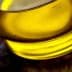 Close-up view of olive oil in a glass container with a yellow hue. - Olive Oil Times