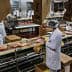 Workers in white coats and hairnets processing meat products on a conveyor belt in a facility. - Olive Oil Times
