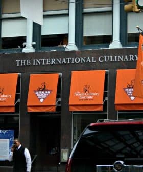 Entrance of the International Culinary Center with orange awnings and signage in New York City. - Olive Oil Times
