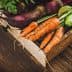 A wooden crate filled with various freshly harvested vegetables, including carrots, beets, and cucumbers. - Olive Oil Times