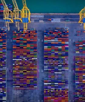 Aerial view of a shipping container yard filled with colorful containers arranged in rows. - Olive Oil Times