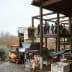 Olive oil production equipment and workers at an outdoor facility with a balcony. - Olive Oil Times