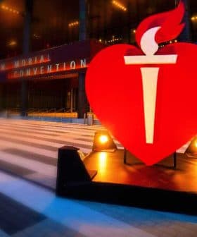 Large red heart symbol with a torch in front of a convention center entrance. - Olive Oil Times