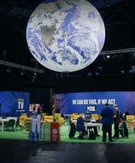 A large globe installation suspended from the ceiling in a conference venue with seating areas below. - Olive Oil Times