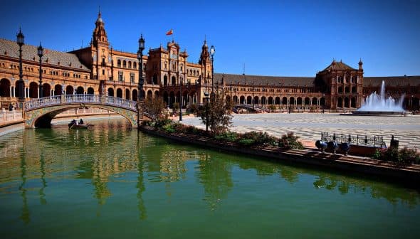 Plaza de España in Seville with a water canal and architectural structures in the background. - Olive Oil Times