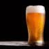 A glass of beer with foam on top, featuring condensation on the outside. - Olive Oil Times