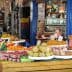 Market stall displaying a variety of fruits and vegetables, with a vendor and a customer wearing masks. - Olive Oil Times
