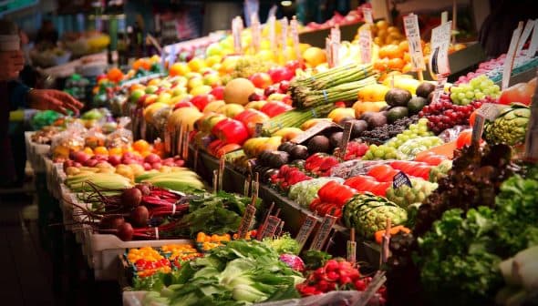 A colorful display of various fresh fruits and vegetables arranged in a market setting. - Olive Oil Times