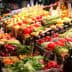 A colorful display of various fresh fruits and vegetables arranged in a market setting. - Olive Oil Times