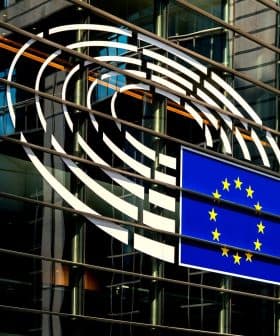 European Union flag displayed on the glass exterior of a building with circular design elements. - Olive Oil Times