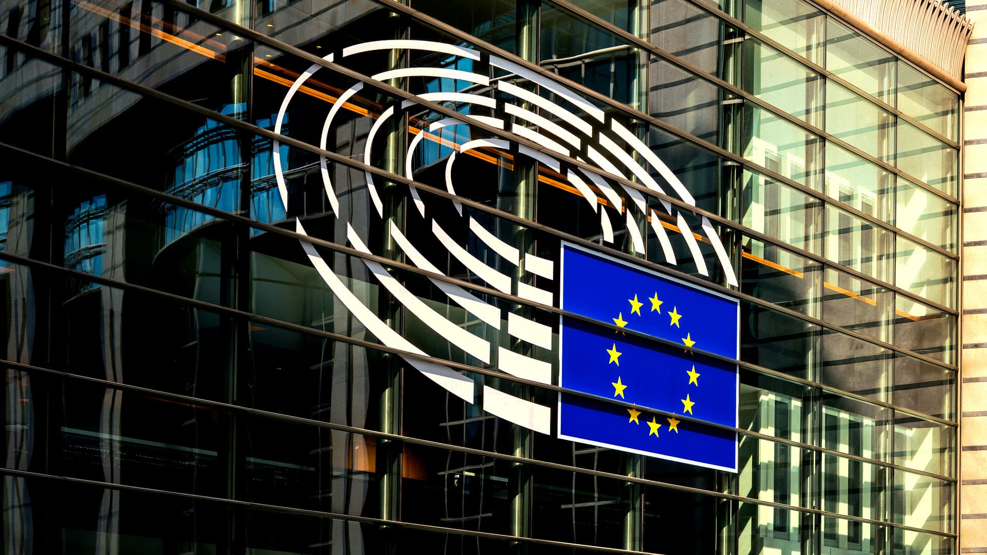 European Union flag displayed on the glass exterior of a building with circular design elements. - Olive Oil Times