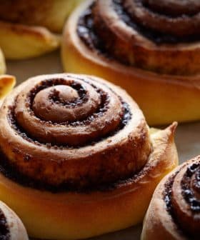 Freshly baked cinnamon rolls with a spiral design on a baking sheet. - Olive Oil Times