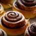 Freshly baked cinnamon rolls with a spiral design on a baking sheet. - Olive Oil Times