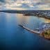 Aerial view of a coastal area featuring a harbor with boats and a shoreline. - Olive Oil Times