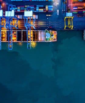 Aerial view of a container port with cranes and cargo containers at night. - Olive Oil Times