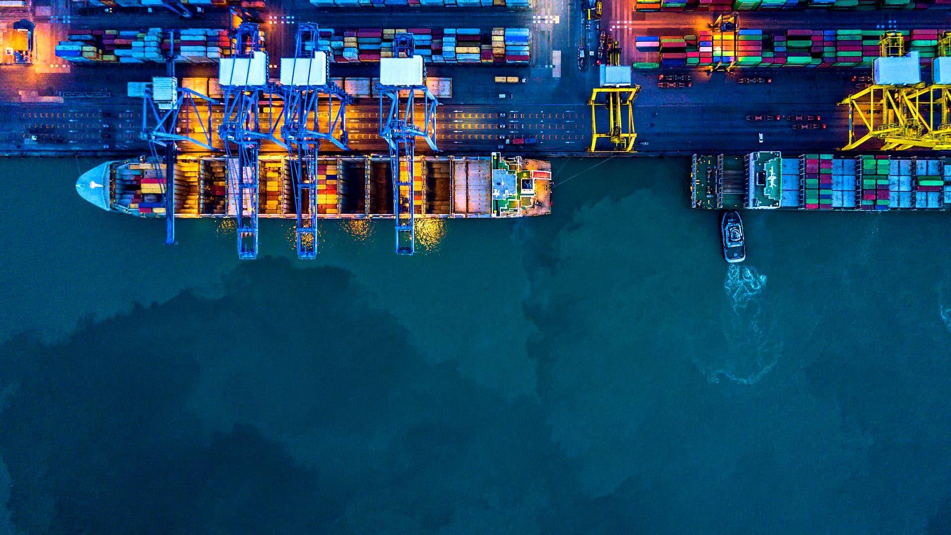 Aerial view of a container port with cranes and cargo containers at night. - Olive Oil Times