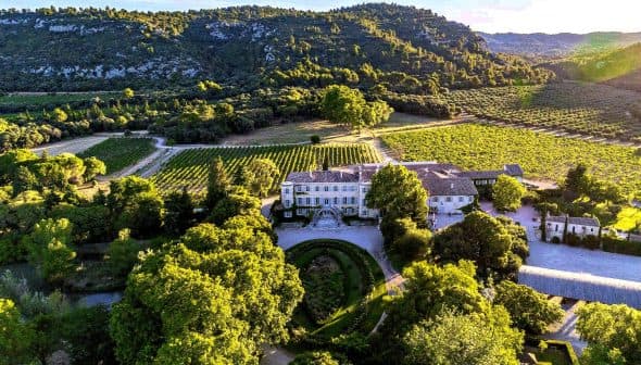 Aerial view of Chateau d'Estoublon surrounded by vineyards and trees. - Olive Oil Times