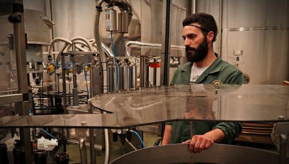 A man with a beard overseeing machinery in an oil production facility. - Olive Oil Times