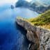 Aerial view of rocky cliffs meeting the blue ocean under a clear sky. - Olive Oil Times