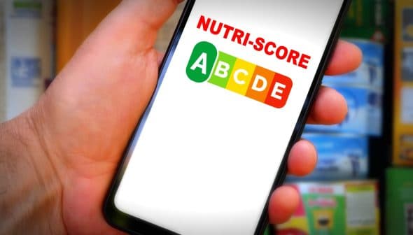 Hand holding a smartphone displaying the Nutri-Score logo with letters A to E in colored boxes. - Olive Oil Times