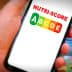 Hand holding a smartphone displaying the Nutri-Score logo with letters A to E in colored boxes. - Olive Oil Times