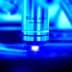 Close-up of a microscope objective lens labeled 100x with a blue background. - Olive Oil Times