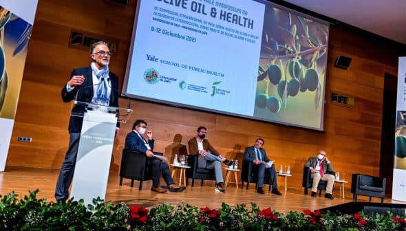 Speaker presenting at the Yale Symposium on Olive Oil and Health with an audience seated in front. - Olive Oil Times