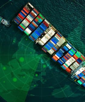 Aerial view of a large container ship loaded with colorful cargo containers on the water. - Olive Oil Times