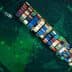 Aerial view of a large container ship loaded with colorful cargo containers on the water. - Olive Oil Times