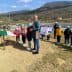 Group of children wearing blue caps at an olive tree planting ceremony with an Italian flag. - Olive Oil Times