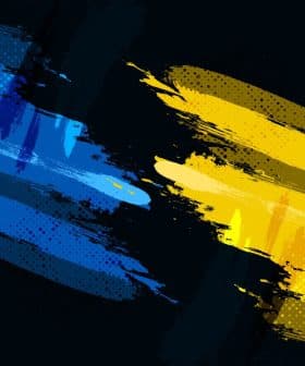 Abstract artwork featuring blue and yellow brush strokes on a dark background. - Olive Oil Times