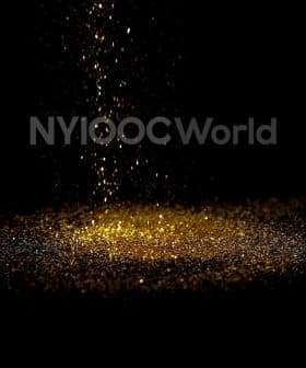 Golden glitter particles falling from above onto a dark surface, creating a shimmering effect. - Olive Oil Times