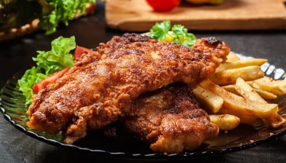 Plate of fried chicken served with French fries and a side of salad. - Olive Oil Times