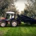 Tractor equipped with olive harvesting equipment parked among olive trees. - Olive Oil Times