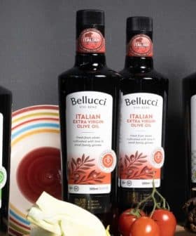 Bottles of Bellucci extra virgin olive oil in various varieties displayed on a table. - Olive Oil Times