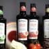 Bottles of Bellucci extra virgin olive oil in various varieties displayed on a table. - Olive Oil Times