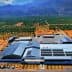 Aerial view of a large olive oil production facility surrounded by olive groves and mountains. - Olive Oil Times