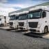 Four white delivery trucks parked in a row at a loading dock area. - Olive Oil Times