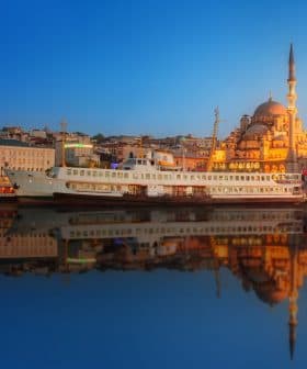 A ferry docked near a mosque in Istanbul during sunset with reflections on the water. - Olive Oil Times