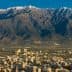 A mountain range with snow-capped peaks in the background and a cityscape in the foreground. - Olive Oil Times