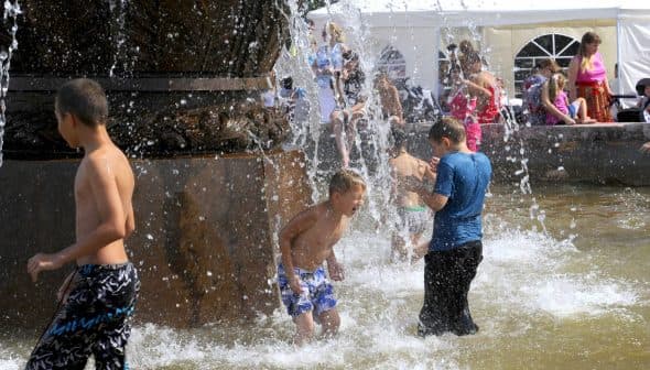 Children splashing water while playing in a fountain on a sunny day. - Olive Oil Times
