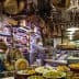 Interior of an Italian deli featuring various meats, cheeses, and a staff member slicing meat. - Olive Oil Times