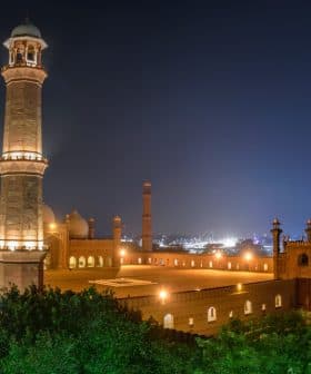 Badshahi Mosque illuminated at night with minarets and domes visible. - Olive Oil Times
