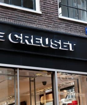Storefront signage of Le Creuset with a black background and illuminated logo. - Olive Oil Times