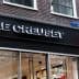 Storefront signage of Le Creuset with a black background and illuminated logo. - Olive Oil Times