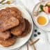 A plate of fried cinnamon French toast served with honey, berries, and a sprig of mint. - Olive Oil Times