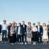 A group of individuals standing together outdoors for a photo against a clear sky. - Olive Oil Times