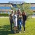 Five individuals standing together outdoors in front of a modern building with greenery. - Olive Oil Times