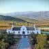 White building of Galenia Estate with mountains and greenery in the background. - Olive Oil Times