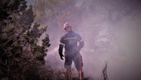 Firefighter wearing protective gear working in a smoky environment during a fire response operation. - Olive Oil Times